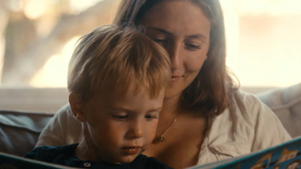 Woman and child reading a book together on a couch