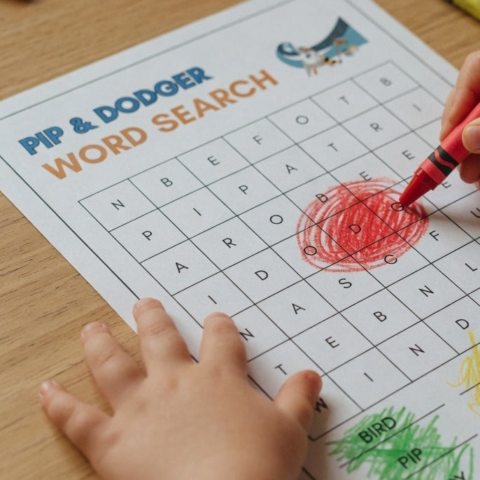 Child coloring a word search sheet with a red crayon on a wooden table.